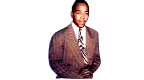 A cutout detail from a colorized black and white photograph where Charlie Parker faces the camera having a wispy mustache wearing a classy suit with wide stripes and an art deco patterned tie.