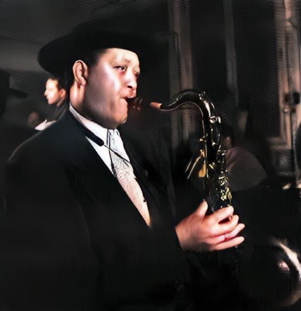 A black and white photograph of Lester Young playing his saxophone while facing in right profile.