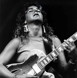 In a  black and white photograph we have Emily Remler with her head leaning back with her eyes closed playing her guitar.
