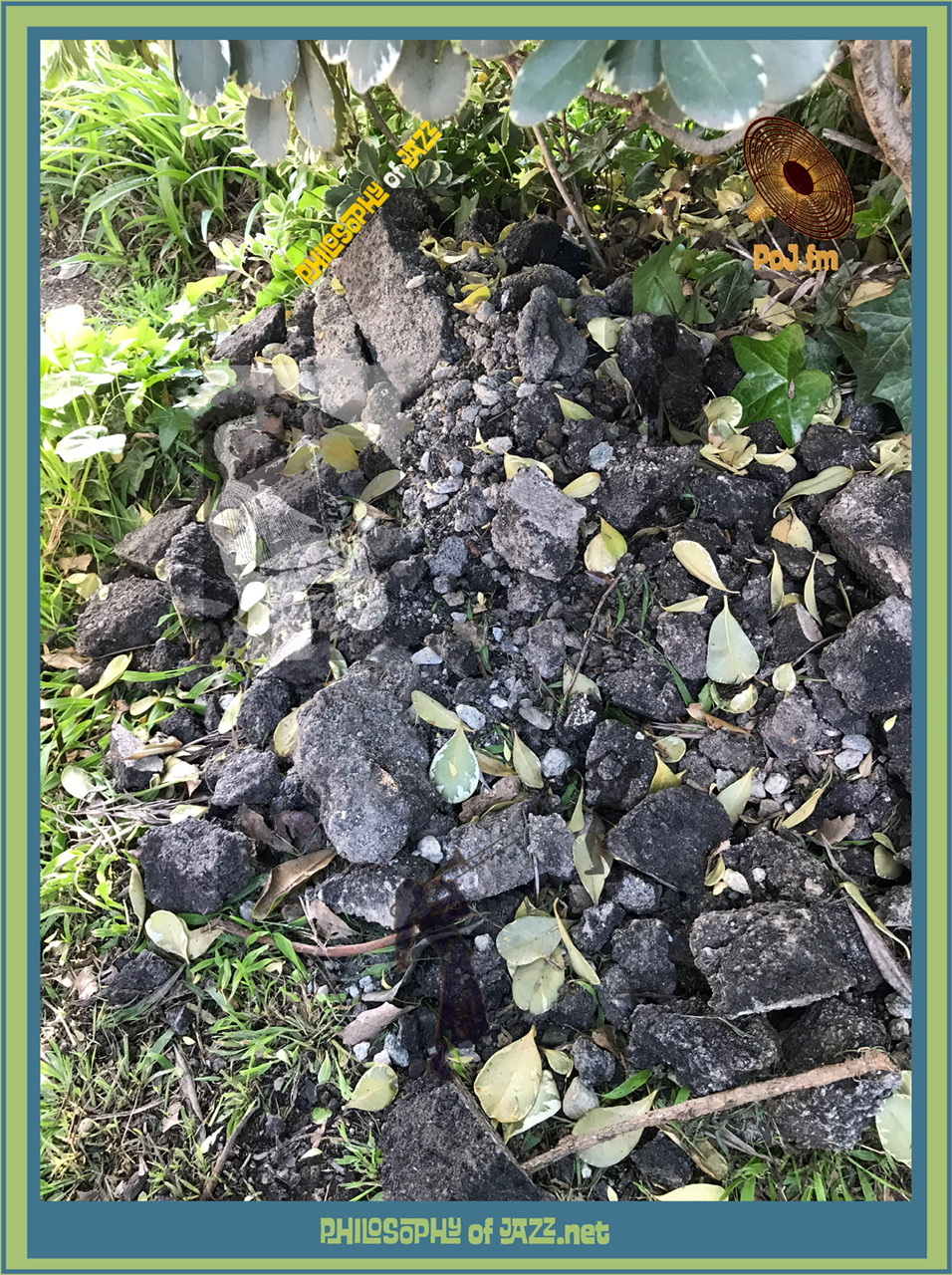 A framed photograph of a jumbled pile of black rocks with four different miniature jazz musician's figures embedded onto the rocks and difficult to discern amongst the shadows on the rocks with PoJ.fm logos.