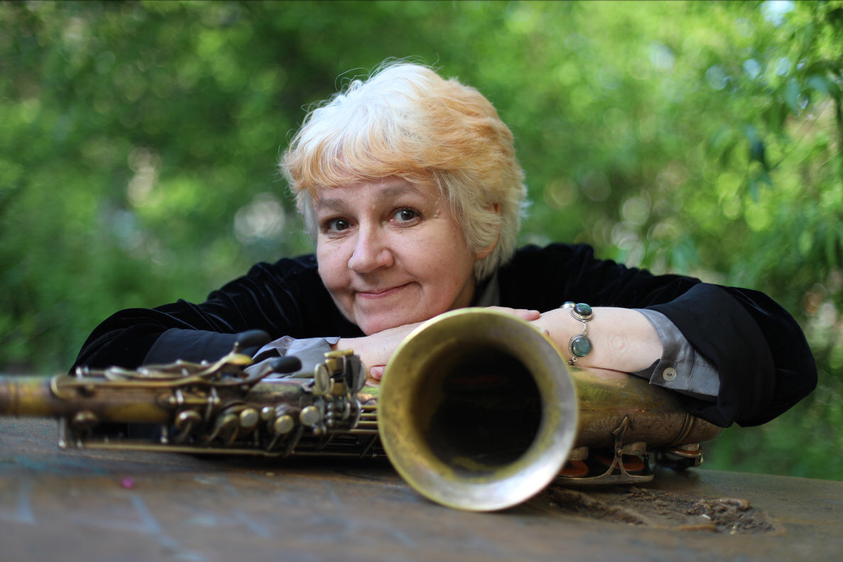 Lena Bloch leaning flat on saxophone with both elbows bent.
