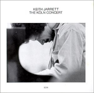 Keith Jarrett's Koln Concert album covering with him facing left hunched over on a piano bench surrounded by white album cover.