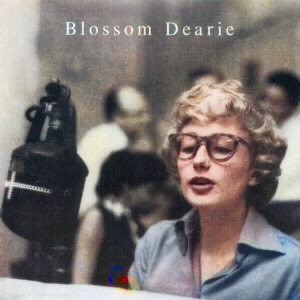 The colorized album cover for the Verve Records debut album for "Blossom Dearie" (Verve 1957) with a picture of Dearie wearing glasses on the cover with out of focus musicians in the background.