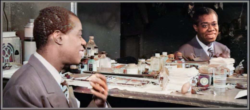 A colorized photograph by William P. Gottlieb of a young man Louis Armstrong looking into a horizontal rectangular dressing room mirror with his mirror image in mirror on right side of photograph.