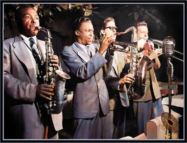 A black and white photograph by Herman Leonard now more colorized of from left to right Charlie Parker, Miles Davis, Allen Eager, and Kai Winding respectively playing the alto saxophone, trumpet with mute, tenor saxophone, and trombone.