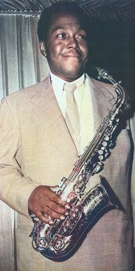 A colorized black and white photograph of Charlie Parker Facing Right and smirking.