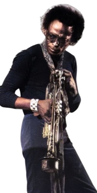 Miles Davis in a blue jean suit blowing his trumpet into a microphone stand probably around early 1970s.