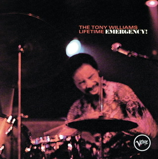 The album cover for "Emergency!" by Tony Williams Lifetime with the title in upper right corner with a closeup of Tony Williams playing his drum kit leaning forward with his eyes closed where the photograph has a pinky-orange tone.