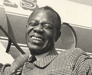 Headshit detail of Louis Armstrong boarding a plane.