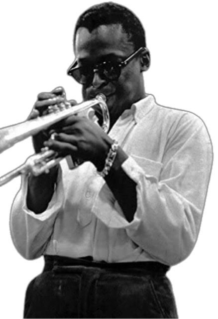 Miles Davis from waist up blowing his trumpet into a microphone stand in Central Park, New York City in 1970.