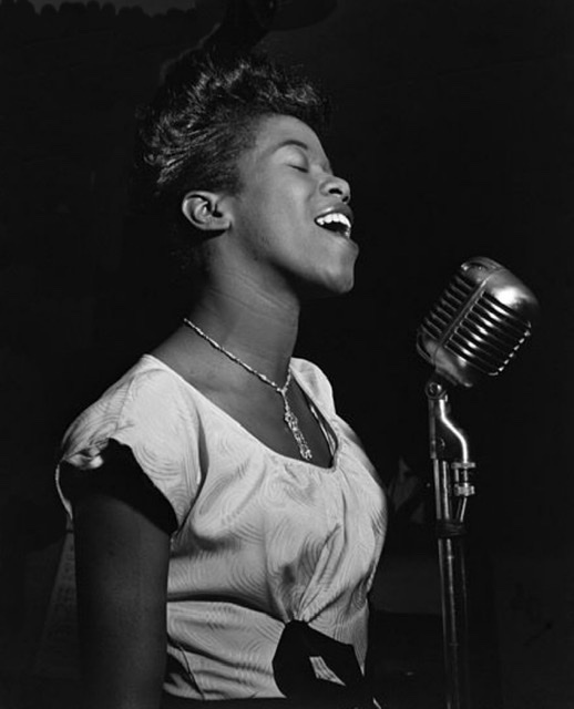 Sarah Vaughn in 1942 singing into a large silver  microphone 🎙.