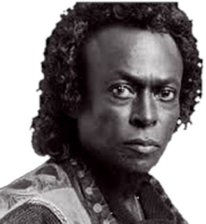 A black and white photograph of the head of late Miles Davis with a lot of hair.