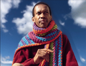 An animated .gif of Don Cherry in a thick colorful knitted scarf wrapped around his neck with a blue sky background and moving clouds.