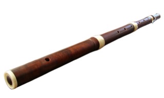 A brown wooden flute laying on its side.