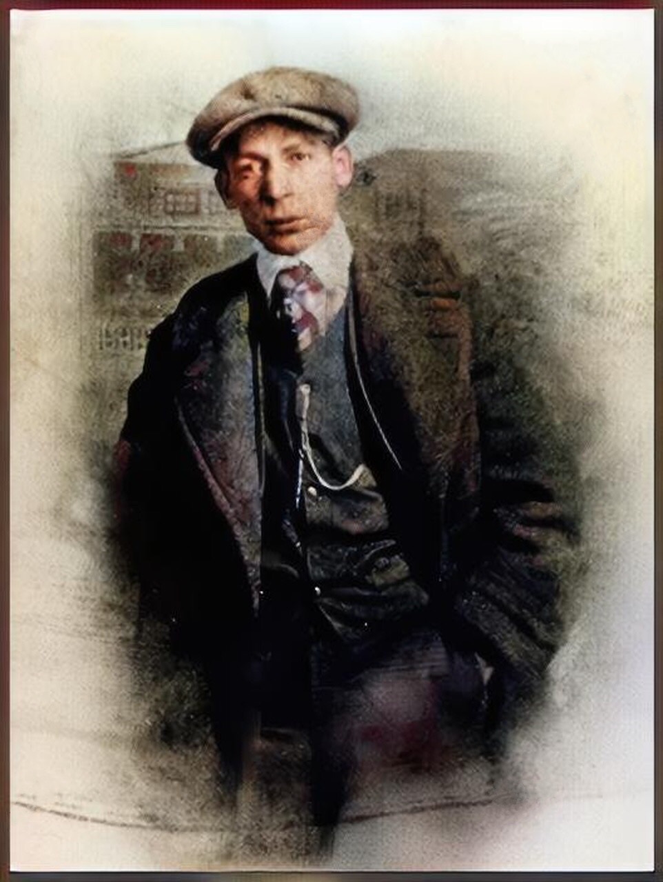 A colorized and healed photograph of a decked out Jelly Roll Morton wearing a cap facing the camera with a jacket and checkered tie tied in a Windsor knot over which he has a thick overcoat with broad lapels with a large buttons vest displaying a hefty cross tied probably gold  chain entering into a vest pocket for pocket watches on his left side (our right).